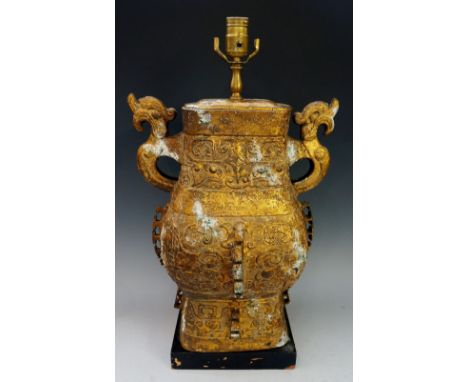 A gold painted metal Chinese style lamp base of archaic form, black rectangular wooden base, 43cm high, 20th Century