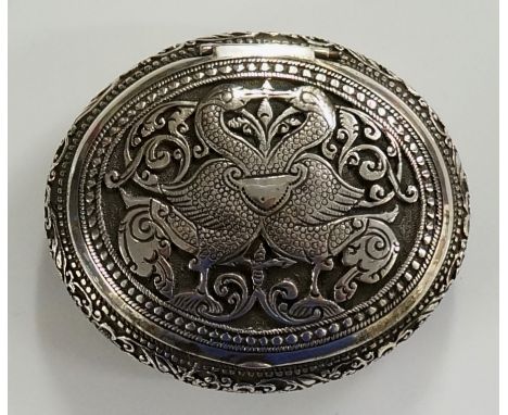 A silver coloured metal oval pill or snuff box, the hinged lid decorated with a pair of birds on a floral trail ground, the b