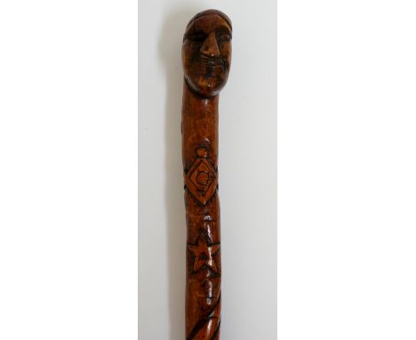 Free Masonry - a walking cane, the terminal carved as a man's face, the tapering shaft carved with various Masonic symbols in