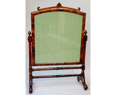 A Victorian rosewood framed fire screen of arched design supported on turned pillars with swept legs joined by horizontal tur