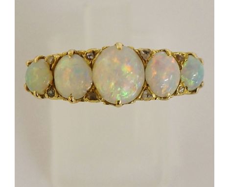 A ladies yellow gold opal ring claw set with five graduated oval opal cabochons, pierced scroll engraved shank, boxed