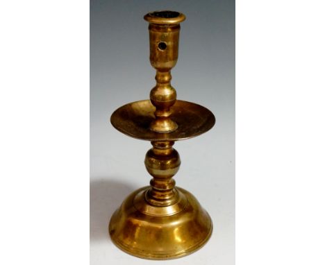 A 17th Century brass candlestick with broad drip pan and knopped stem, trumpet shaped base, 20cm high