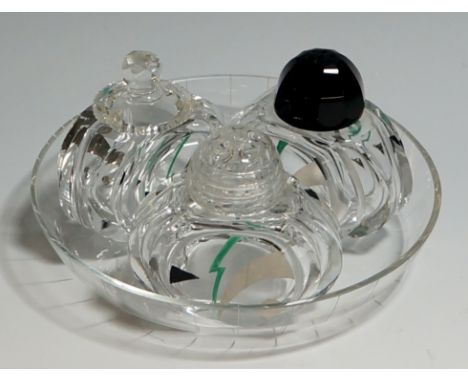 An Art Deco glass three piece cruet set on circular tray, the sides of each pot decorated with black, green and silver enamel