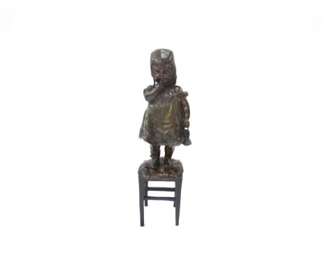 JUAN CLARA AYATS (1875-1958): A bronze sculpture of young girl standing on a rush seated stool, holding boots, finger pressed