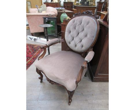 Stamped "Wilkinson &amp; Son, Bond Street" A mid Victorian carved walnut open armchair, the oval buttoned back rest over scro