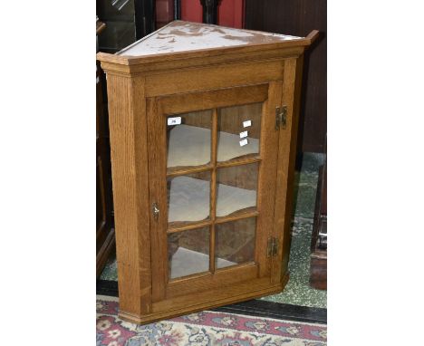 A modern light oak wall mounted corner cabinet with glazed panel door