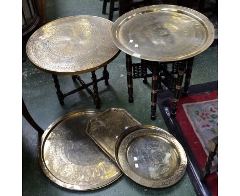 A folding brass top table, the stand inlaid with bone mother of pearl; a large Persian style circular tray; others similar; a