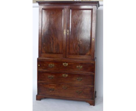 George III mahogany linen press, the upper part of two panelled doors enclosing two drawers and later sliding shelves, on a b