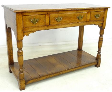 A reproduction oak sideboard, in the Georgian style, with three frieze drawers, brass plate handles, raised on turned front l