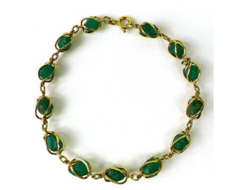 An 18ct gold and uncut emerald bracelet of thirteen stones each in a twisted gold wire surround, each stone approximately 5.5