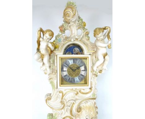 A modern Rococo style long case clock, with carved and painted case surmounted by putti, chiming movement with moon roller to