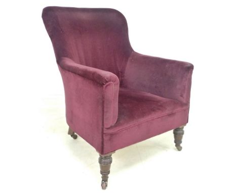 A Victorian spoon back armchair, upholstered in burgundy velvet, raised on turned front legs, with brown ceramic castors, 66 
