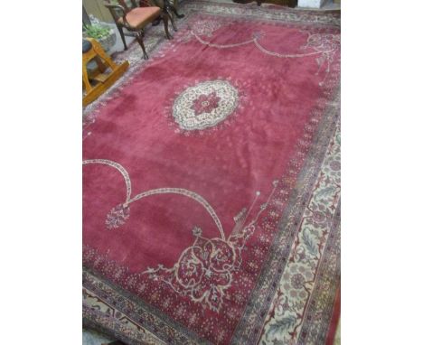 A large red ground carpet having a central medallion, floral design and multiguard borders, 190" x 140" 