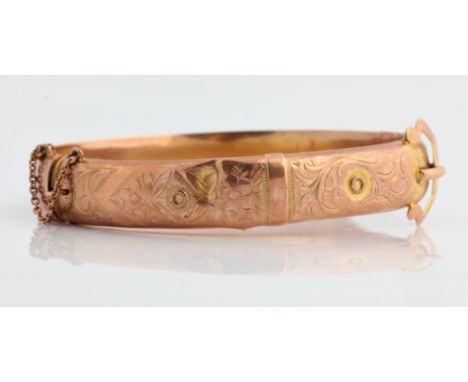 A hallmarked 9ct yellow gold engraved hinged buckle design bangle with safety chain, approx. weight 12g. IMPORTANT: Online vi