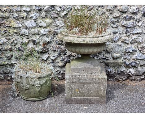A weathered composition stone urn and pedestal,&nbsp;73cm high x 58cm diameter; together with another similar smaller planter
