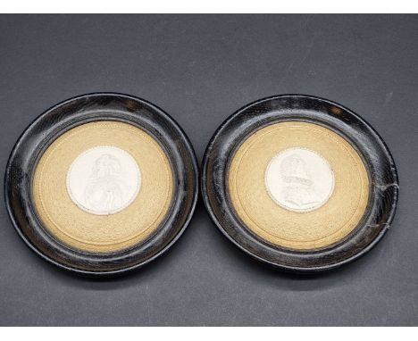 A pair of 19th century buff pottery pot lids, each decorated with a Renaissance style portrait, in ebonized frames, 14cm diam