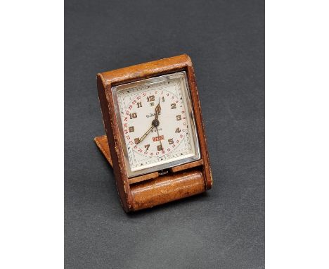 A 1930s LeCoultre eight day travel calendar alarm clock, in folding tan hide case, 8.5cm. 