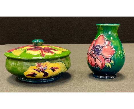 A Moorcroft Hibiscus pattern trinket pot and cover, tube lined with large flowerheads in tones of red, yellow and green, on a
