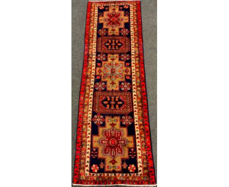 An Azerbaijan runner carpet, hand-knotted in red, cream, and deep blue, 332cm x 109cm. 