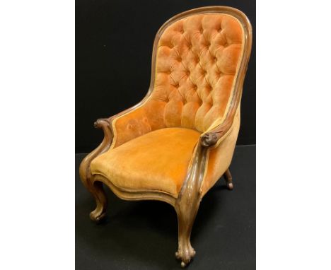 A Victorian walnut  nursing chair, shaped button back and stuffed-over seat, carved arm rests, cabriole legs, brass castors, 