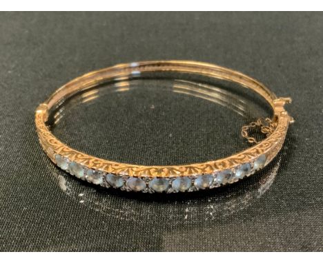 An Edwardian diamond and aquamarine hinge bangle, inset with eleven old round cut aquamarines each divided by rose cut diamon