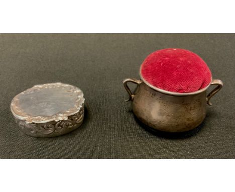 A silver oval snuff box, embossed with scrolls, 4.5cm wide, marked 925;  a silver cauldron pin cushion, 4.5cm high, Chester c