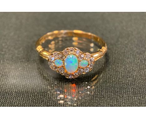 A diamond and opal cluster ring, with three oval opals flashing green, red and violet colour, surrounded by nineteen diamonds