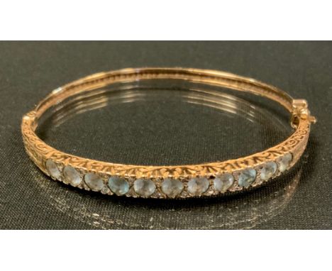 An Edwardian diamond and aquamarine hinge bangle, inset with eleven old round cut aquamarines each divided by rose cut diamon
