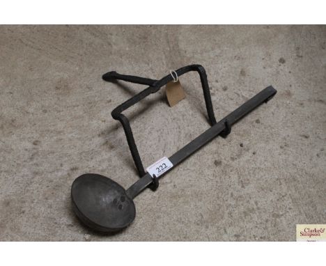 An antique pewter ladle and an iron hearth rack