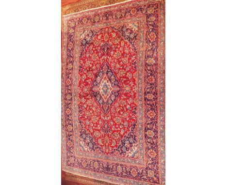 A fine Central Persian Kashan carpet, central double pendent medallion with repeating spandrels and petal motifs on a rouge f