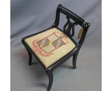 An early 20th century ebonised harp stool, with tapestry upholstered seat, raised on sabre legs 