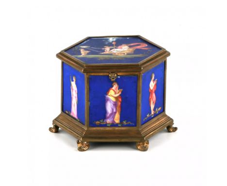 A brass box with porcelain panels, in the shape of a hexagon, bears images of the muses on a blue background. The lid panel i