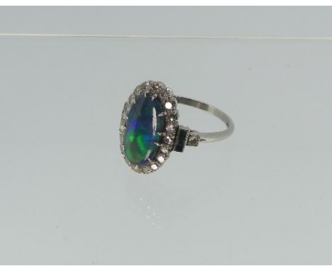 A black opal and diamond dress Ring, the oval opal with good colours of bands of green, dark blue and flashes of red, the sto