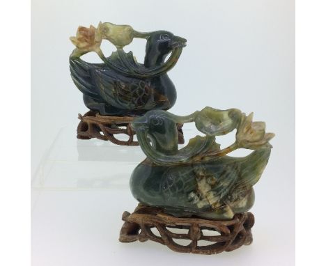 A pair of early 20thC Chinese jade Ducks, each holding a lily in its beak, on wood stands, with silk-lined box, each duck 3¼i