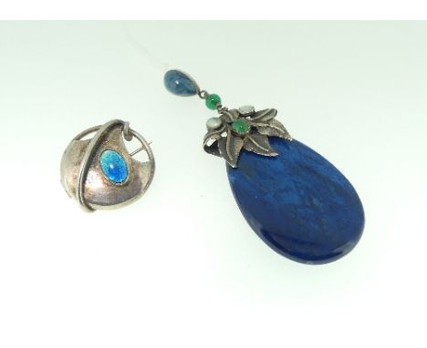 A blue agate teardrop shaped Pendant, with white metal foliate mount set with green stones and mother of pearl, all suspended