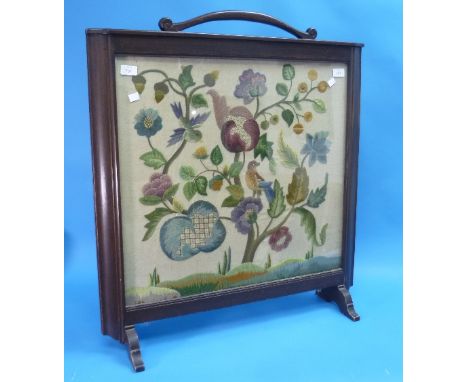An early 20thC Woolwork Firescreen, in the style of William Morris depicting exotic birds among flowers, in a dark wood frame