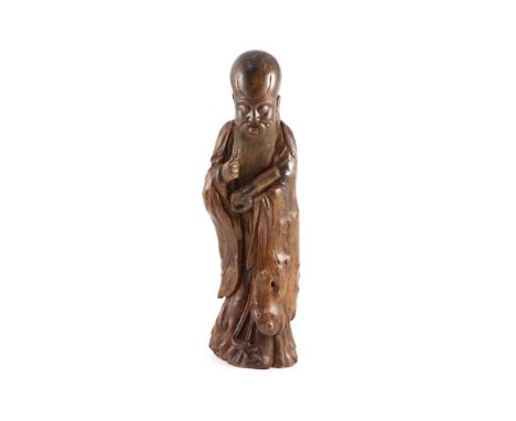 A tall Chinese rootwood figure of Shou Lao, 17th/18th century,the standing figure holding a scroll in his left hand, remnants