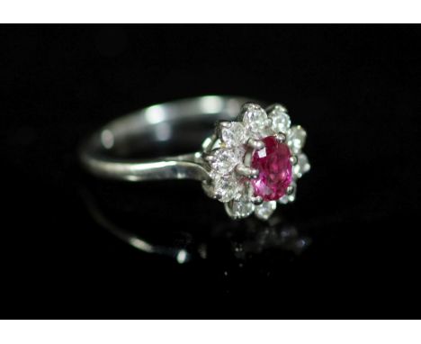 A white gold, ruby and diamond set flower head cluster ring,with central oval cut ruby, size R, gross weight 4.7 grams.