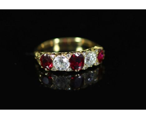 A Victorian style gold, three stone ruby and two stone diamond set half hoop ring,with carved shoulders, each diamond weighin