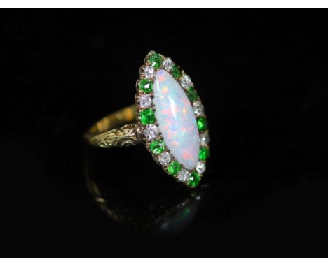 An early 20th century 18ct gold, white opal, green garnet and diamond set navette shaped dress ring,with carved shoulders, si