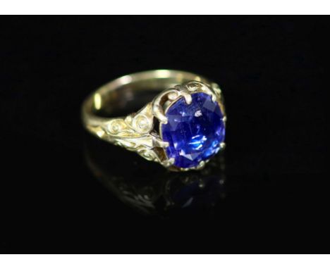 An 18ct gold and single stone claw set sapphire ring,with closed back setting and carved shoulders the stone measuring approx