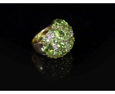 A Continental 18k gold and graduated round cut peridot encrusted dress ring, with diamond chip spacers,size M/N, gross weight