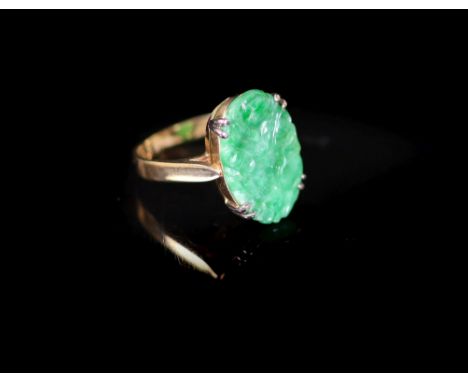 A mid 20th century gold and carved oval jade set dress ring,size O, gross 5.9 grams.