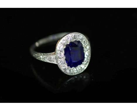 A 1930's platinum and gold, sapphire and diamond set oval cluster ring,the setting and shoulders with engraved decoration, th