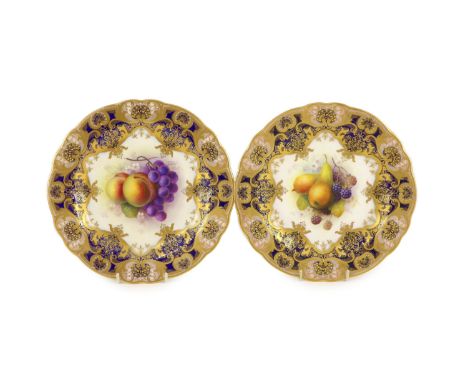 A pair of Royal Worcester fruit painted dessert plates, signed A. Shuck, c.1918,each within gilt-decorated cobalt blue and pi
