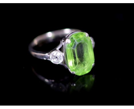 A 9ct white gold oval cut peridot set dress ring, with diamond set shoulders,size M, gross weight 3.1 grams.