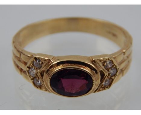 A 9 carat yellow gold, diamond and garnet gents ring, in the Art Deco taste, set oval cut garnet flanked by six small diamond