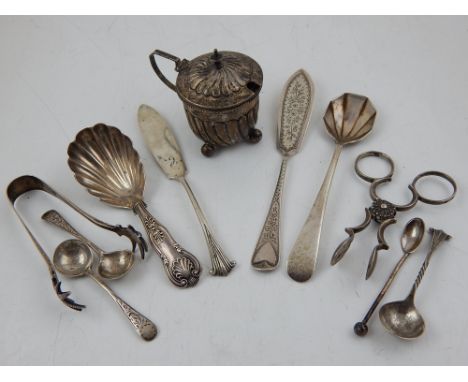 A pair of early 19th century silver sugar nips, a Victorian silver caddy spoon, two butter knives, 5 condiment spoons and two