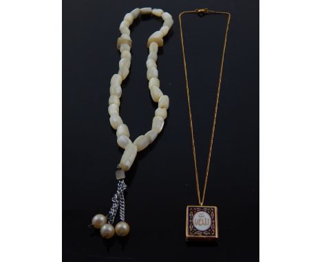A yellow metal pendant in the form of a Quran, together with a mother-of-pearl beaded necklace. (2)