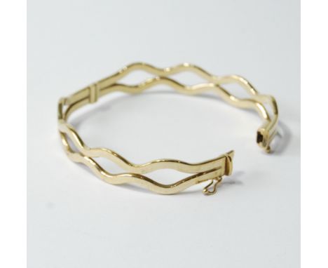 Gold hinged bangle of waved form, '375'. Condition Report 8g